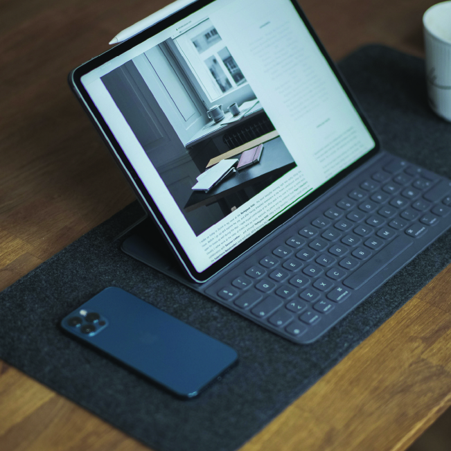 Laptop and phone set up on a dark wooden desk